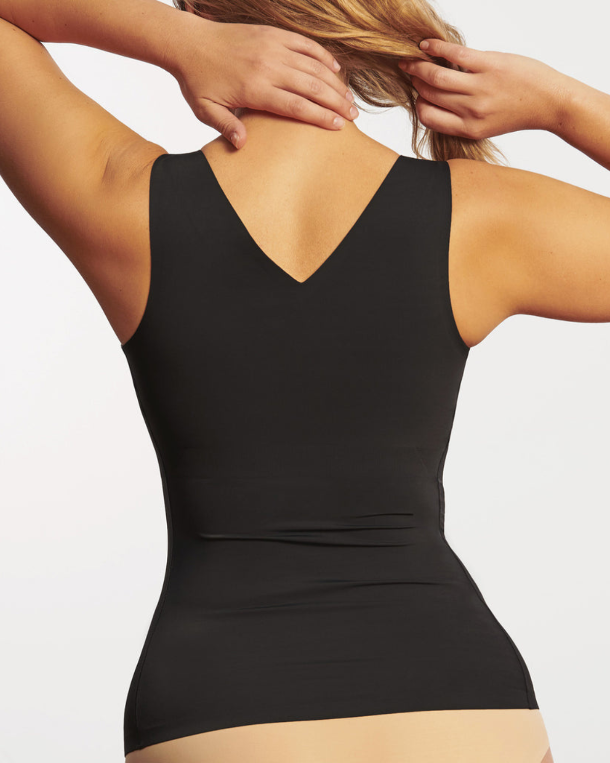 Model on white backdrop wearing a smoothing in cami with built in wire-free bra in black