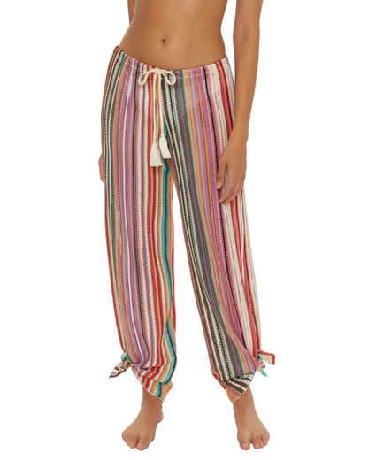 Model wearing a split multi-way cover up pant with adjustable ties at the ankle in a striped red, green, white, pink and orange print