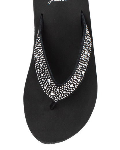 Top view of a black wedge sandal with rhinestones on the strap on a white backdrop.