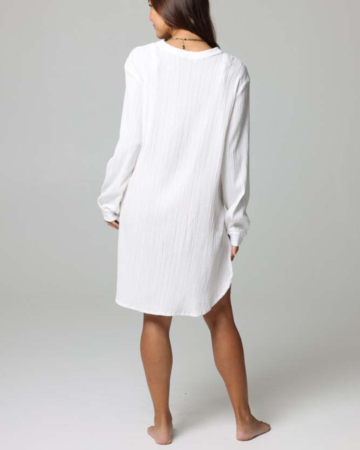 Model wearing a long sleeve button up oversized cover up shirt in white