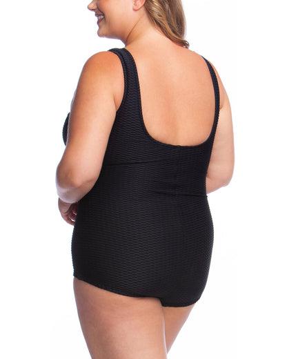 Plus size model wearing a textured one piece swimsuit with a girl leg cut in black