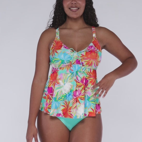 Model rotating 360 degrees wearing a babydoll style tankini with hidden underwire in an orange, turquoise, white and pink floral print.