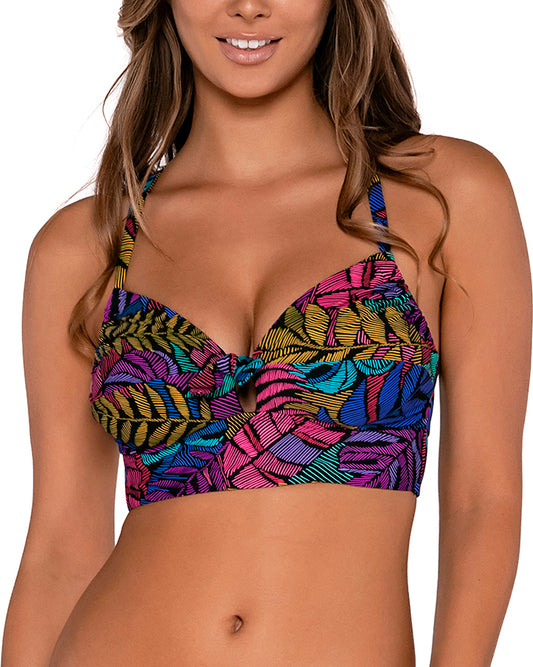 Model wearing a bralette style bikini top in a pink, purple, blue and yellow palm frond print.