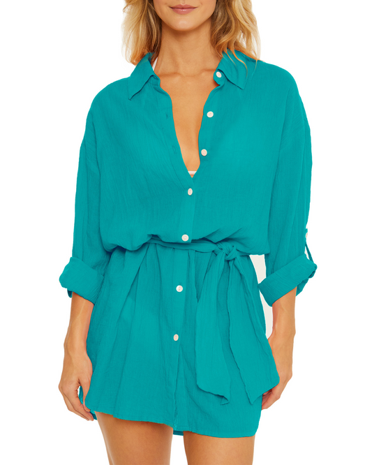 Model wearing a gauzy button up shirt dress in turquoise