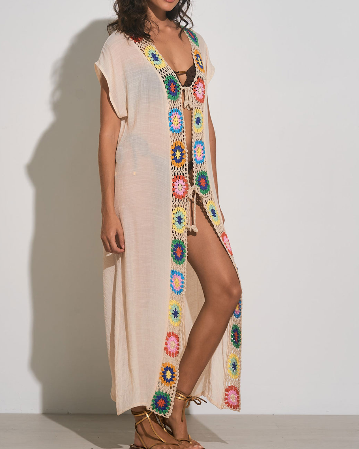 Model wearing a maxi length short sleeve kimono cover up with square crochet detail in beige, green, yellow, blue, and orange