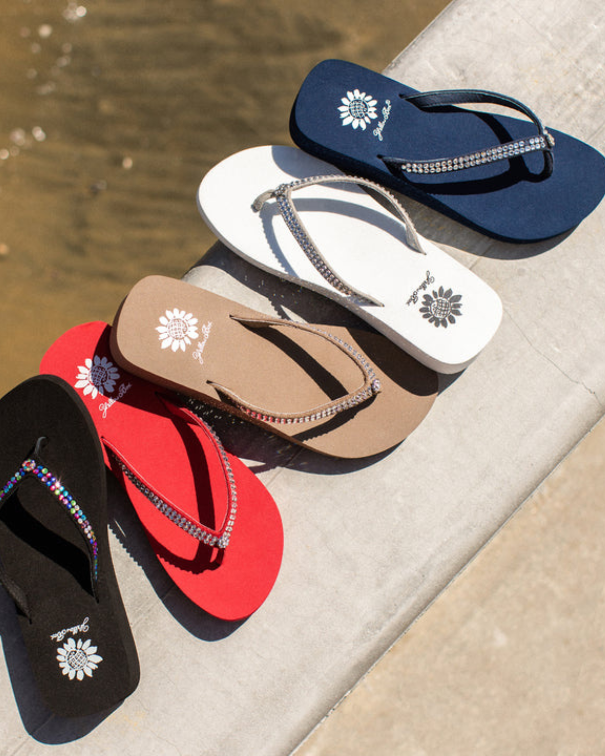 A group of women's multi colored wedge sandals with rhinestones on the strap. From left to right it shows black, red, taupe, white and navy.