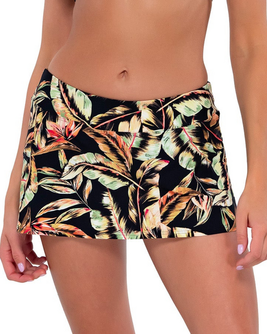 Model wearing a swim skirt with side pocket and hidden short in a black, green and red tropical print.