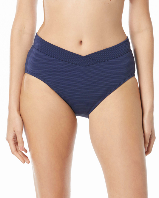 Model wearing a pique texture crossover v-front mid rise bikini bottom in navy