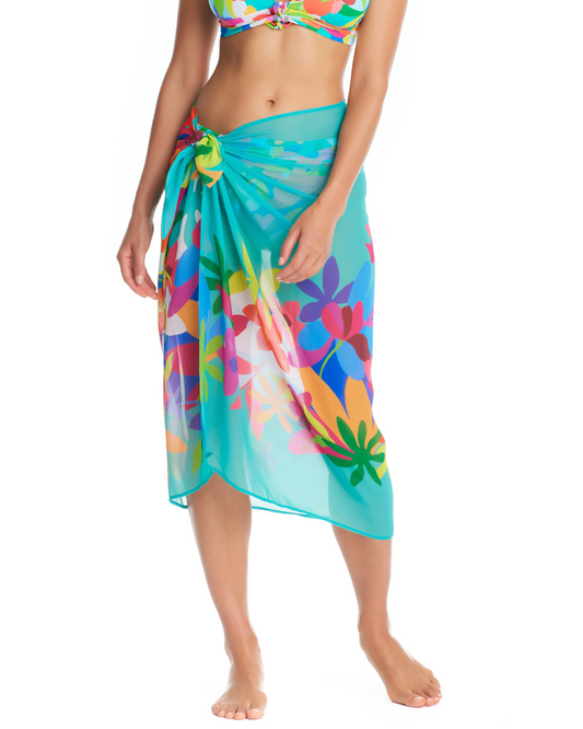 Model wearing a pareo cover up with a turquoise base and yellow, green, purple, blue, and white abstract floral details.