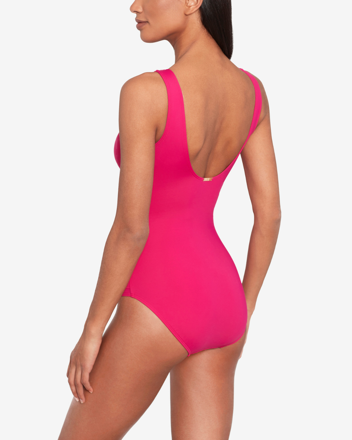 Model wearing a v-neck one piece with a ruffle trim and shirred panel around the torso in pink