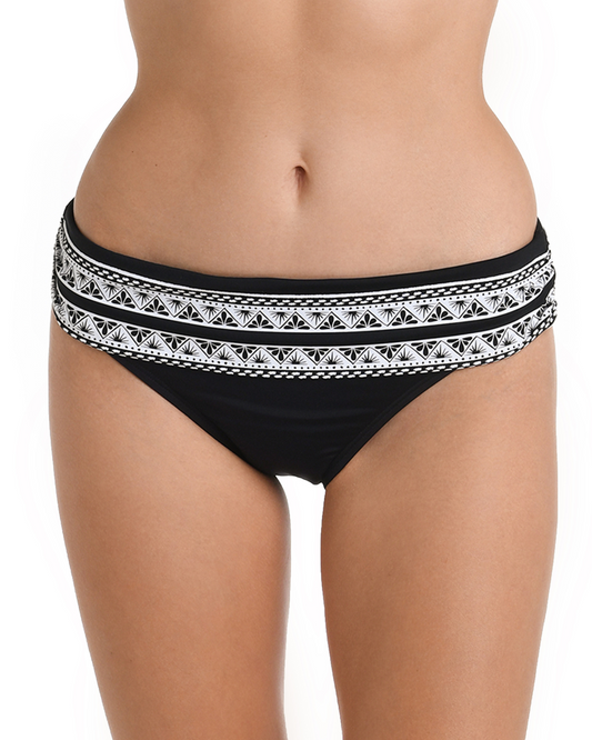 Model wearing a hipster banded bikini bottom in black with a white ornate print on the band