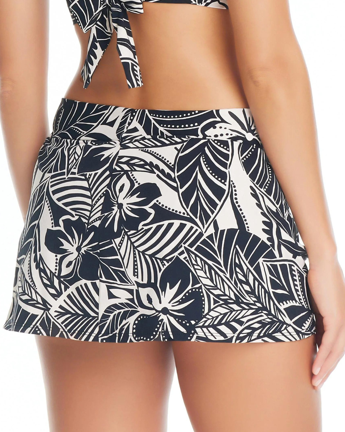 Model wearing a draped swim skirt in a black and white Hawaiian floral print.