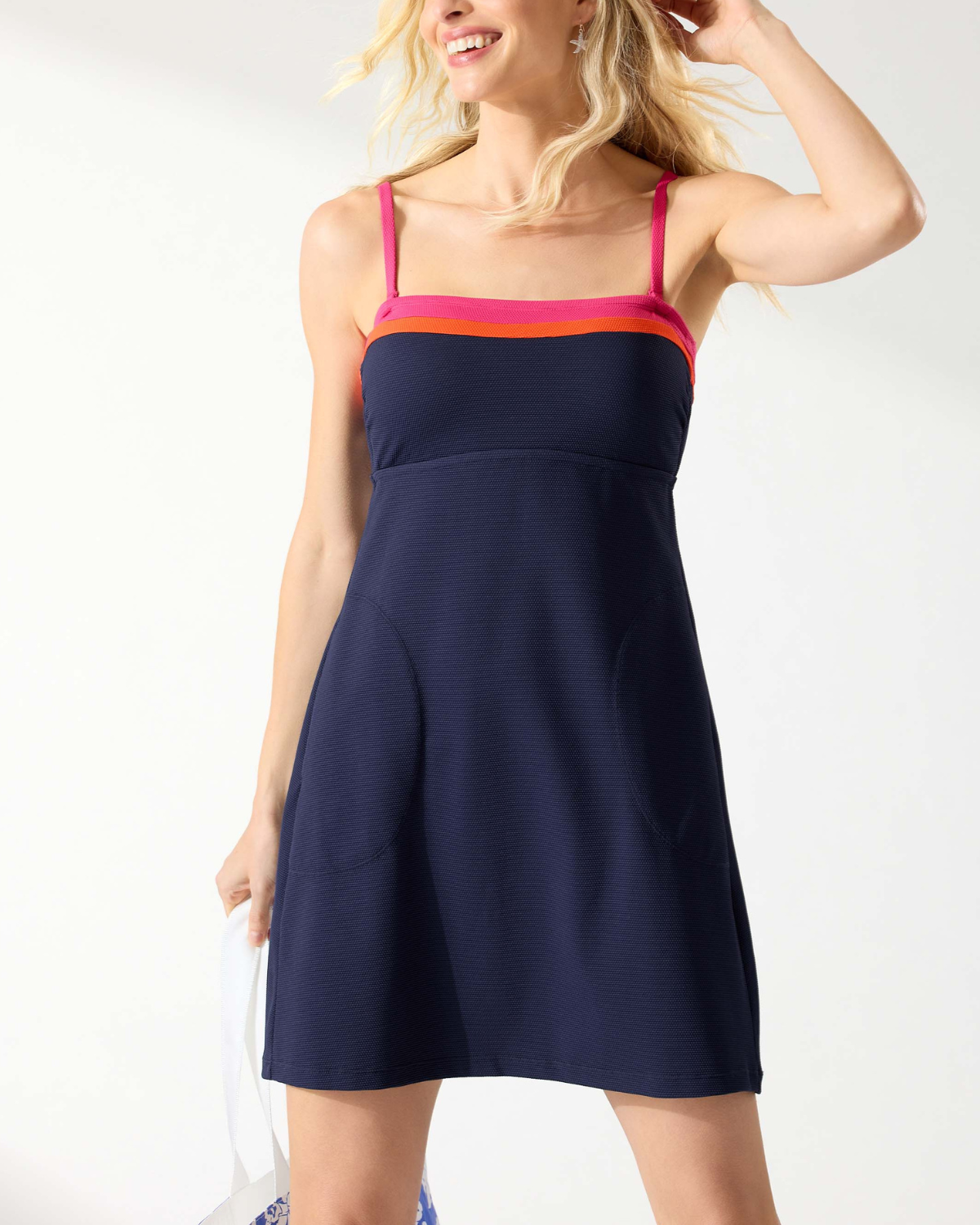 Model wearing a strapless bandeau spa dress with pockets in navy with a pink and orange stripe on the neckline