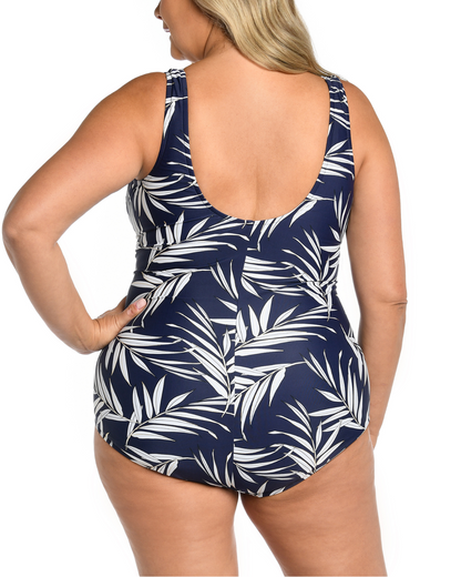 Plus size model wearing a one piece girl leg cut swimsuit in a navy and white palm frond print