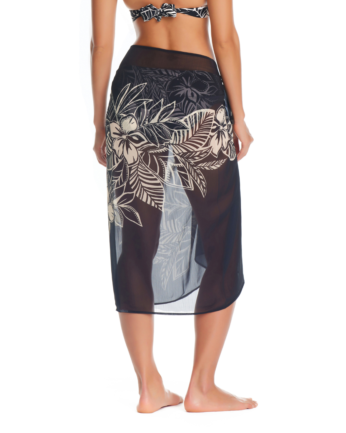Model wearing a pareo cover up with a black base and white tropical Hawaiian floral detail