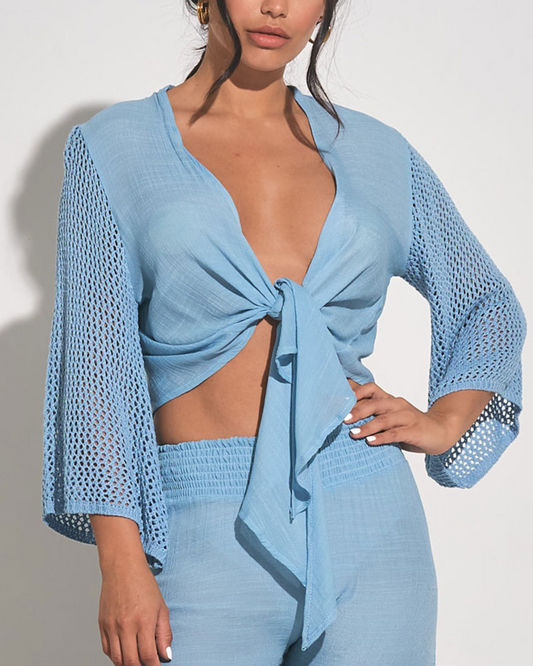 Model wearing a 3/4 sleeve tie front top with crochet sleeve in light blue