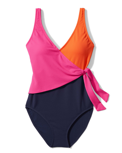 Flatlay of a one piece wrap swimsuit in a colorblock print in navy, pink and red