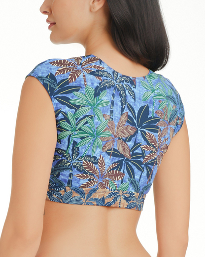 Model wearing a cropped tie front cap sleeve bikini top in a navy, brown and green palm frond print