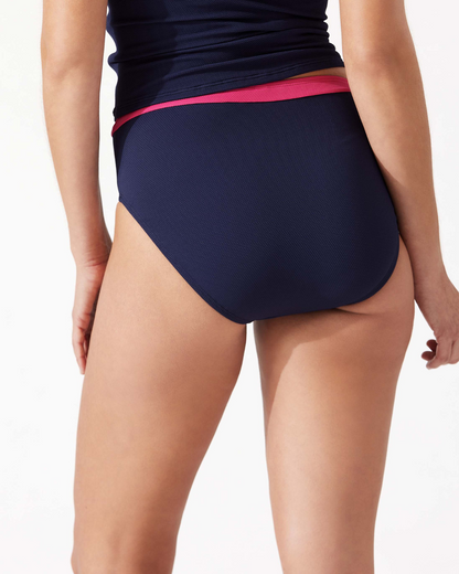 Model wearing a high waist bikini bottom in navy with a pink stripe at the top