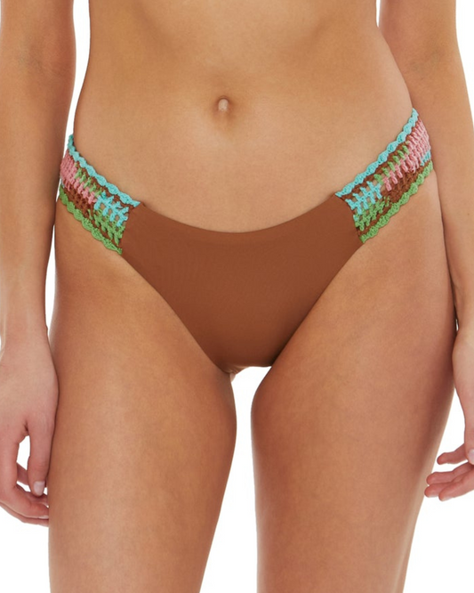Model wearing a hipster bikini bottom in brown with crochet tab side detail in brown, turquoise, pink and green