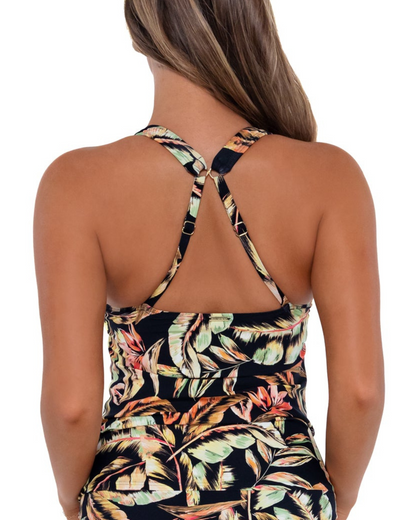 Model wearing a crossover tankini top in a black, green and red tropical print.
