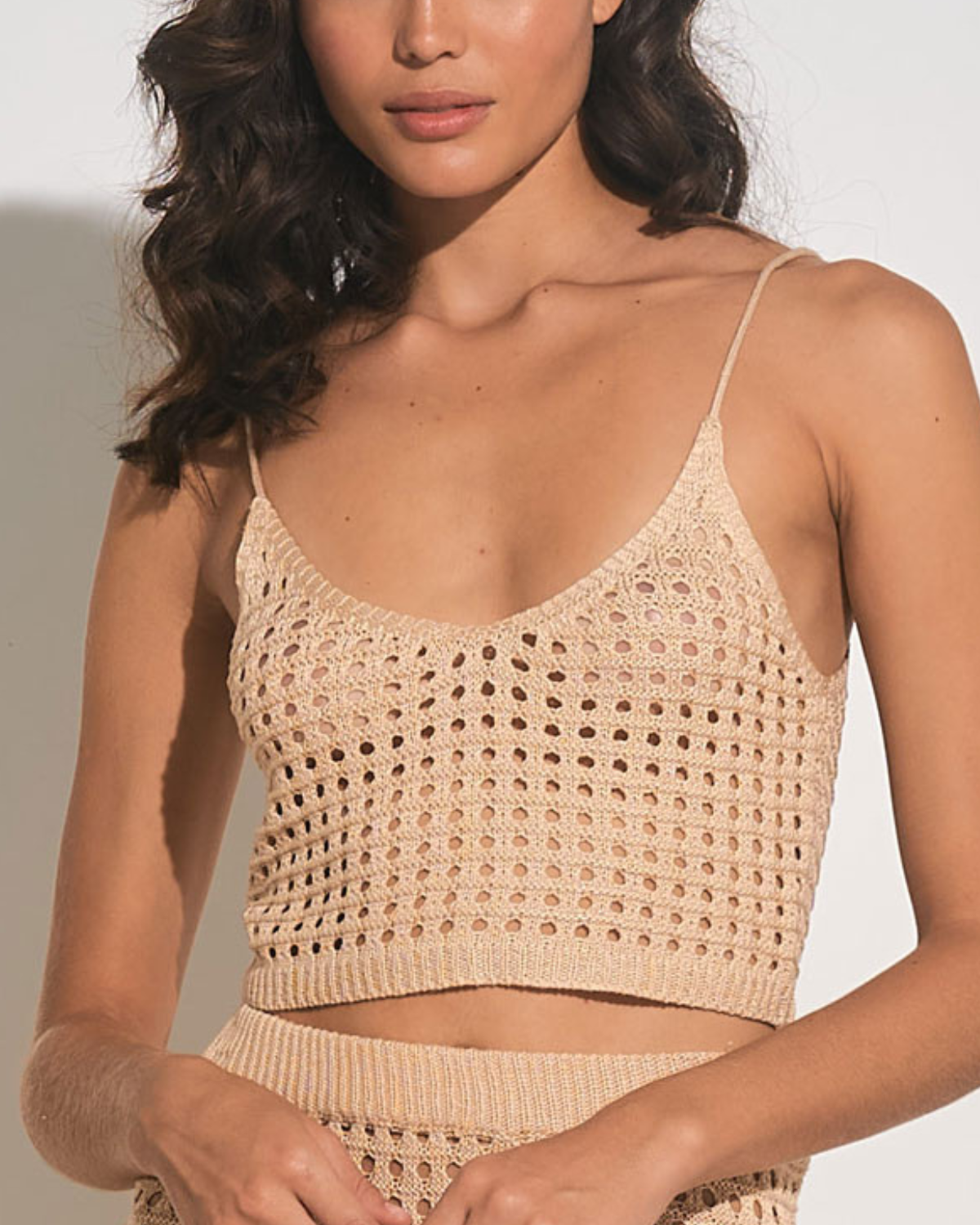 Model wearing a cropped crochet top in tan