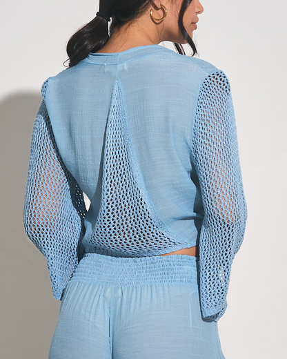 Model wearing a 3/4 sleeve tie front top with crochet sleeve in light blue