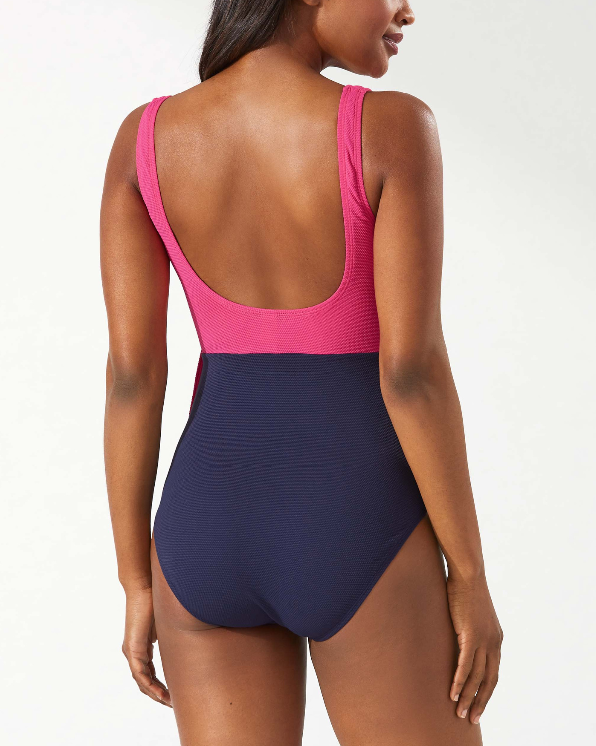 Model wearing a one piece wrap swimsuit in a colorblock print in navy, pink and red