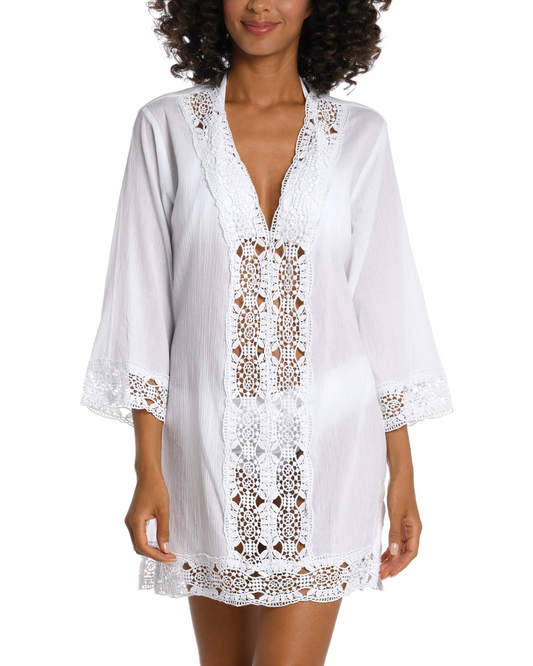 Model wearing a 3/4 sleeve v-neck tunic with a crochet trim in white