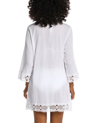 Model wearing a 3/4 sleeve v-neck tunic with a crochet trim in white