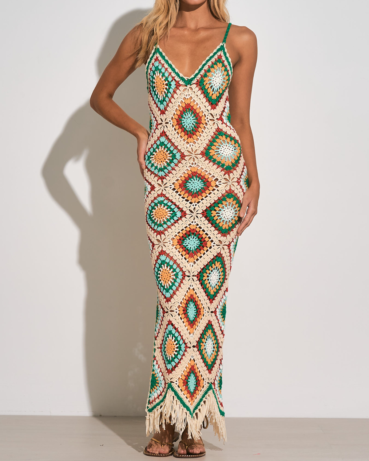Model wearing a diamond pattern crochet maxi dress in white, green, turquoise, yellow and orange