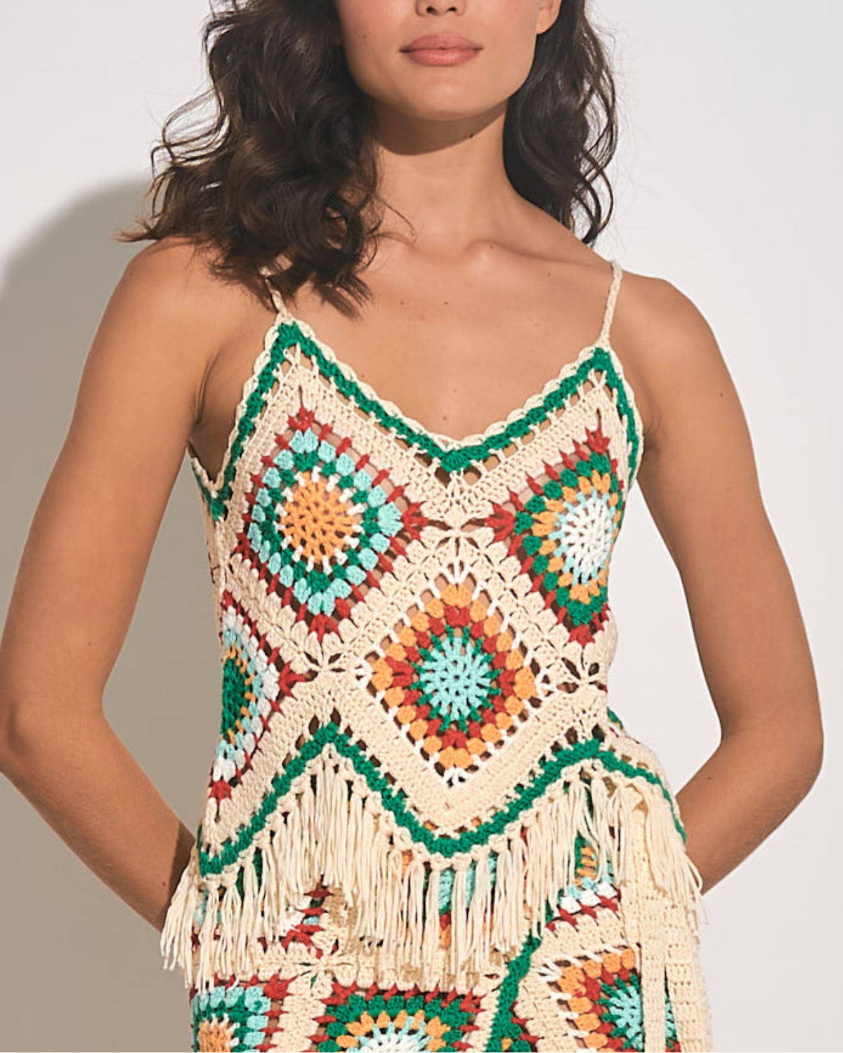 Model wearing a crochet tank top in white, green, yellow, blue and red
