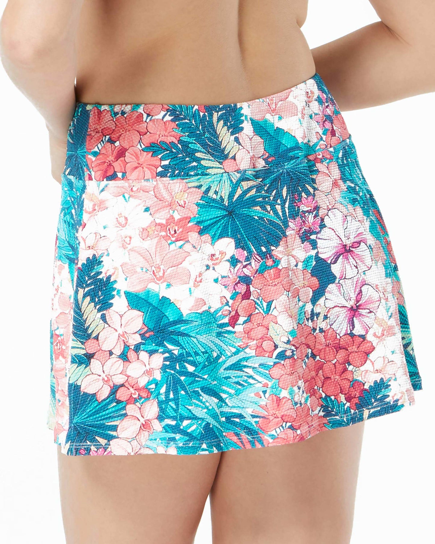 Model wearing a swim skirt with shorts underneath in a blue, green, pink, red and white floral print