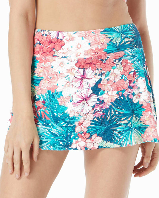Model wearing a swim skirt with shorts underneath in a blue, green, pink, red and white floral print