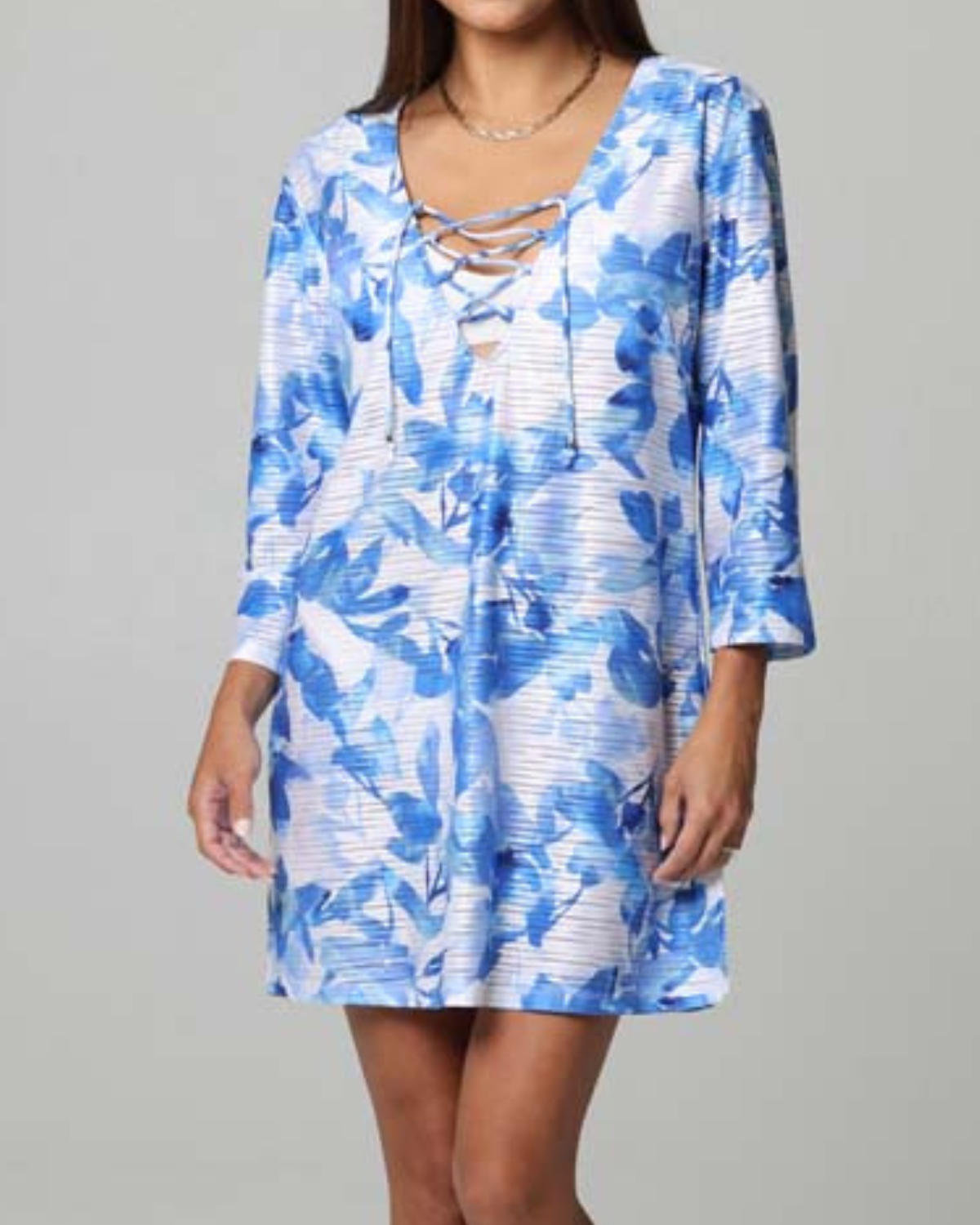 A model wearing a 3/4 sleeve dress with a v neck and lace up detail in a white and blue floral print