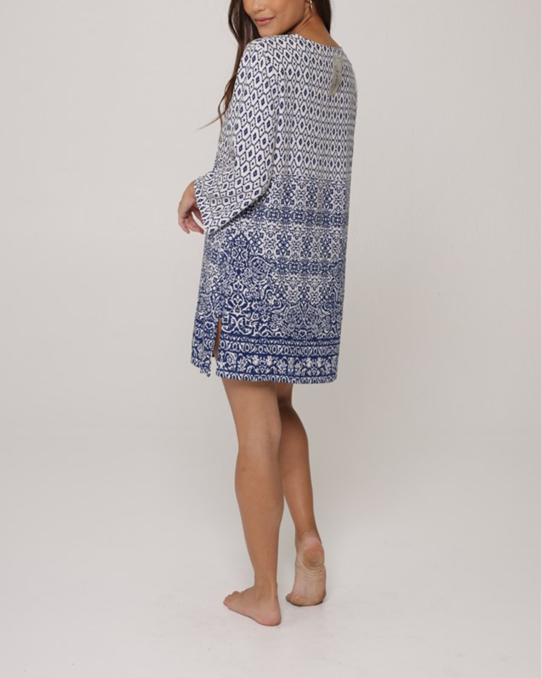A model wearing a tunic dress in a navy and white ornate print