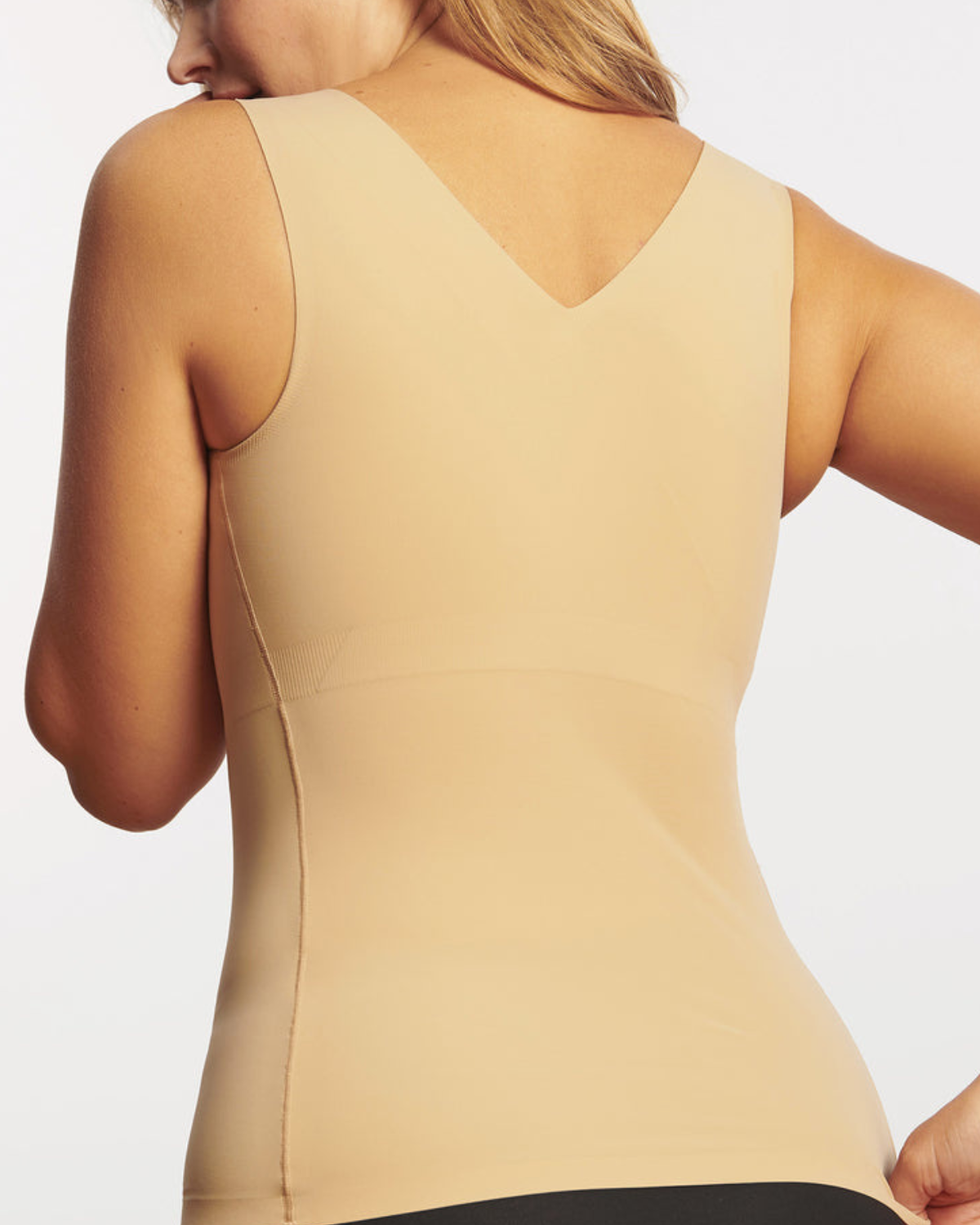 Model on white backdrop wearing a smoothing in cami with built in wire-free bra in beige