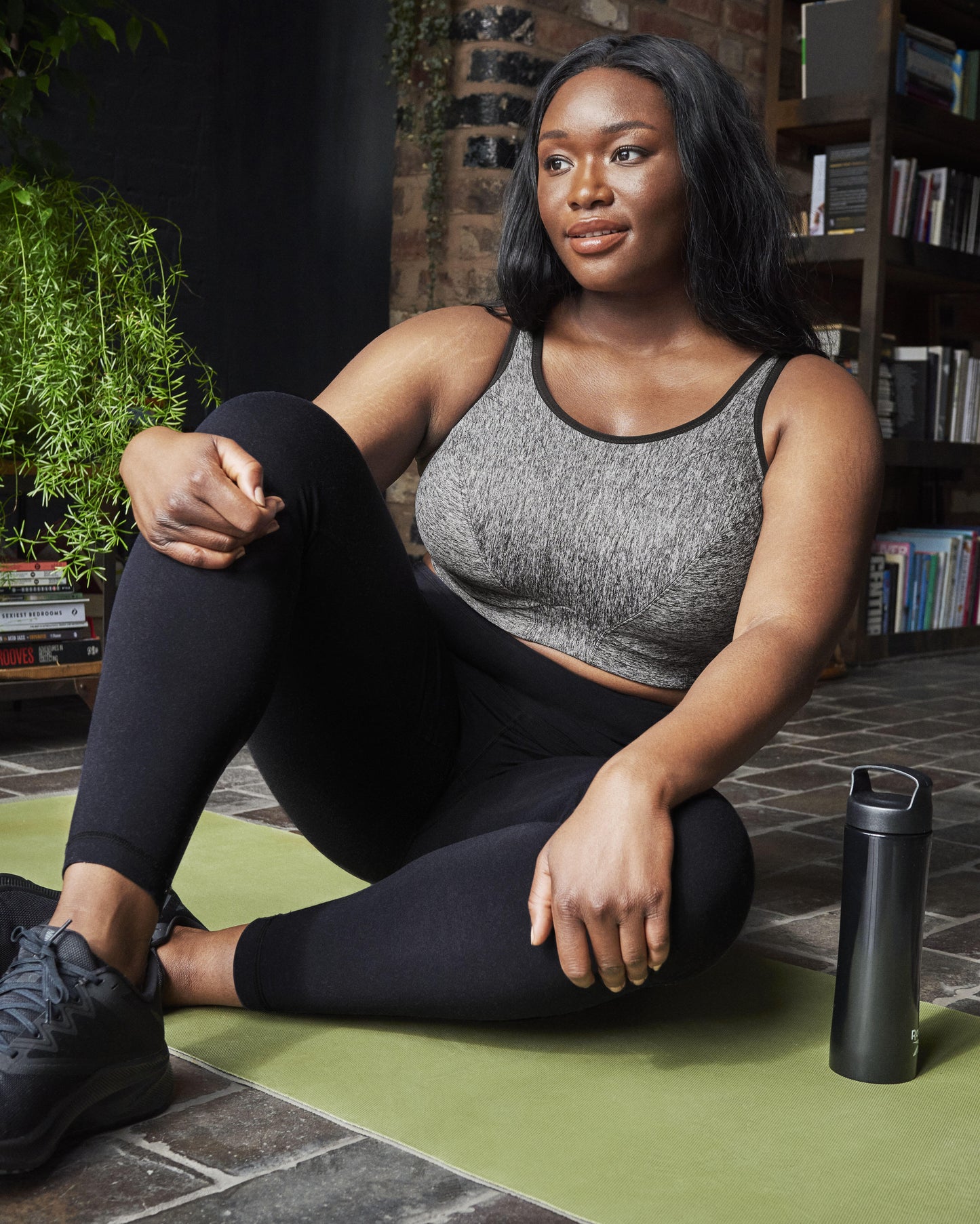 Model sitting on a yoga mat wearing a wire free sports in grey