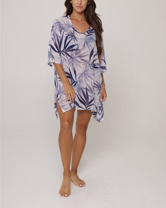 Model wearing a beach cover up tunic in a blue and white tropical pint