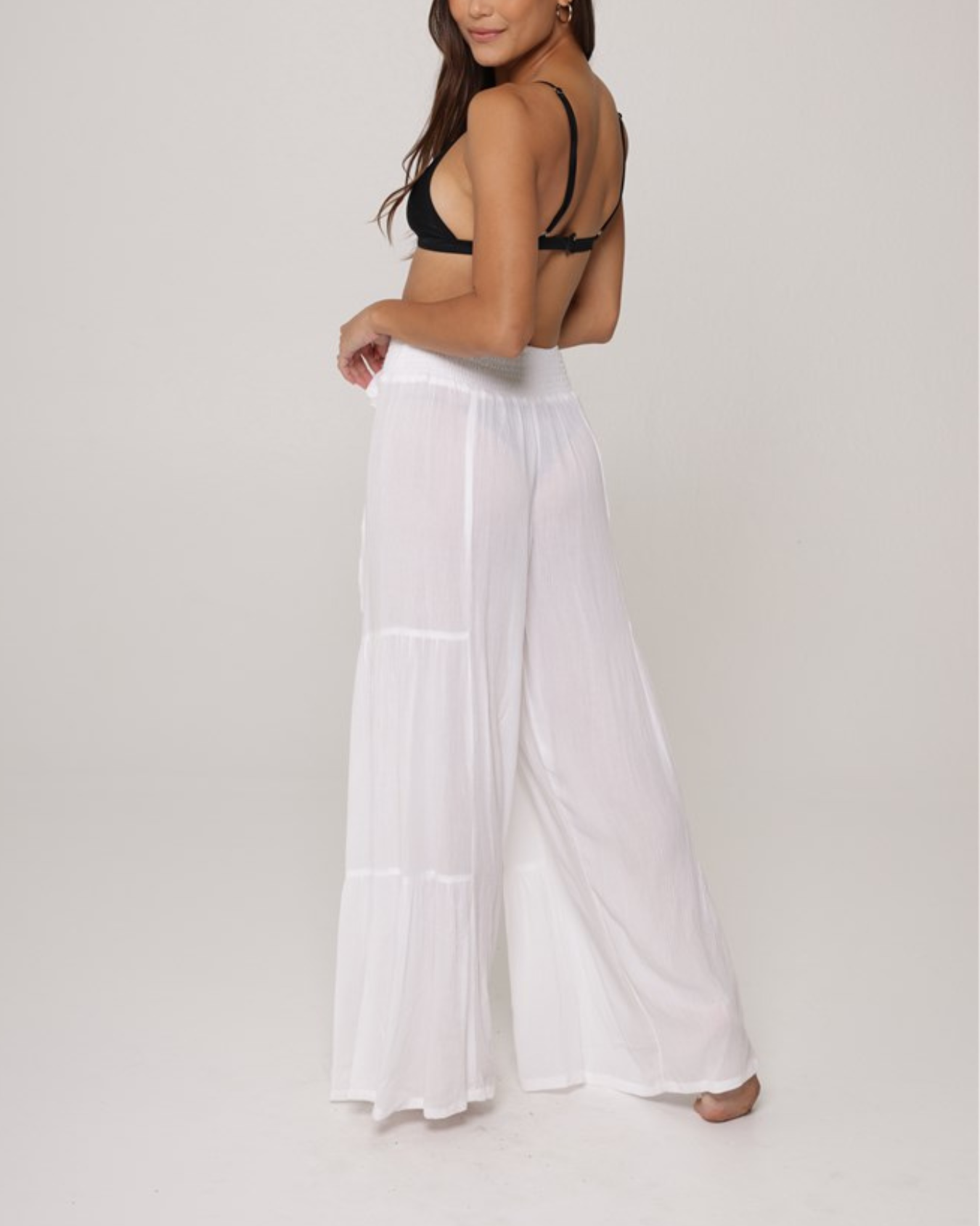 Model wearing a tiered cover up pant with tie belt in white