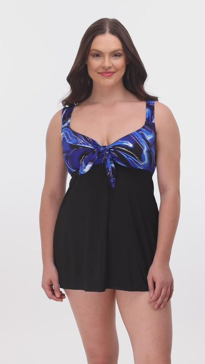 Modeling turning 360 degrees wearing a tie front swim dress in black with a black and blue marble print top