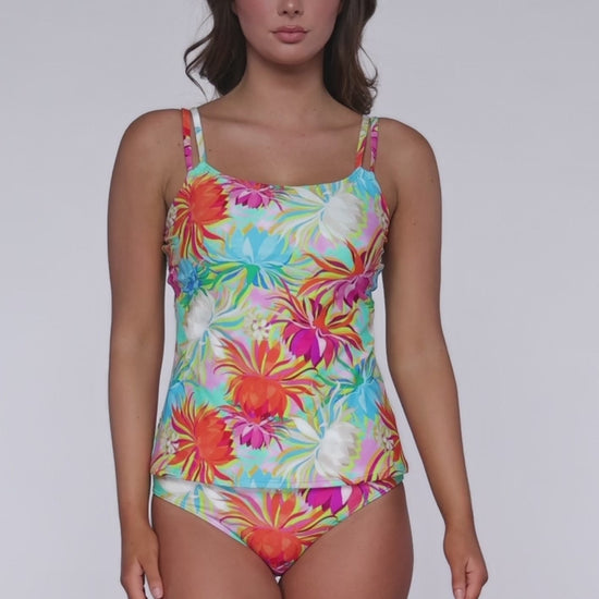 Model rotating 360 degrees wearing a tankini top with hidden underwire in an orange, white. pink, turquoise and yellow floral tropical print.