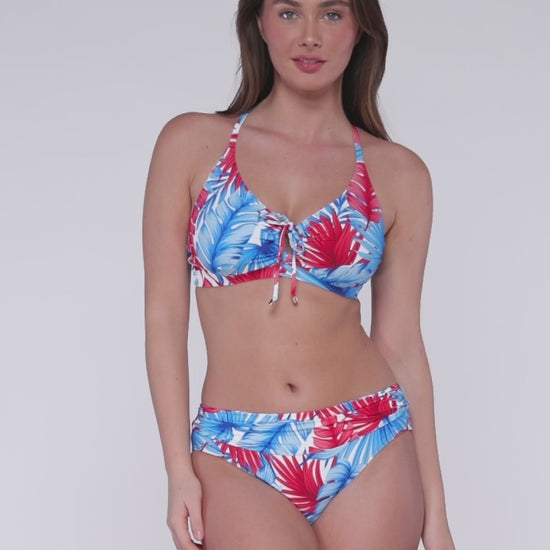 Model rotating 360 degrees wearing a keyhole bikini top with hidden underwire in a red, white and blue palm frond print with matching hipster bikini bottoms.