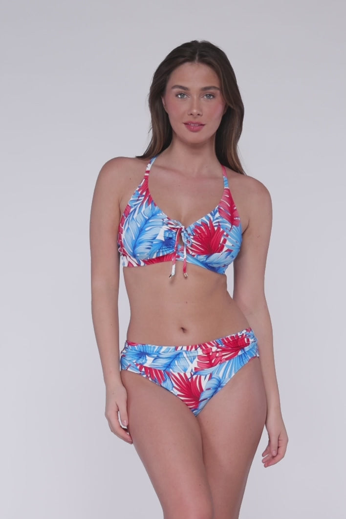 Model rotating 360 degrees wearing a keyhole bikini top with hidden underwire in a red, white and blue palm frond print with matching hipster bikini bottoms.