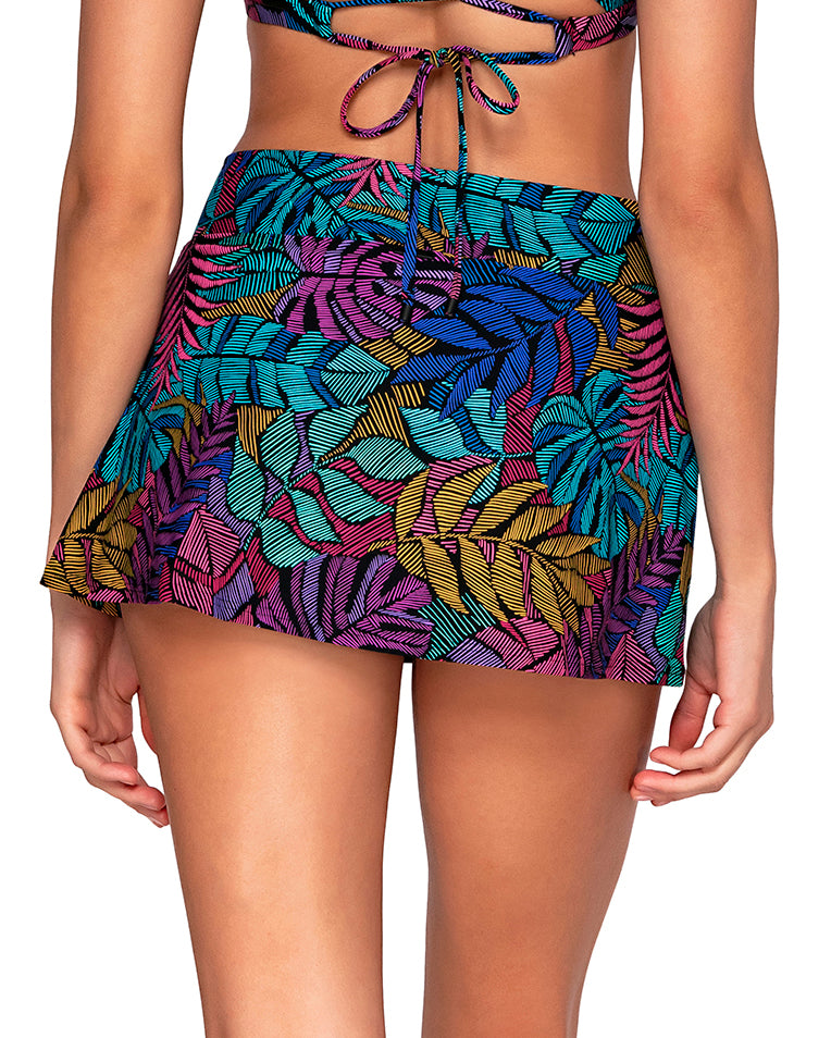 Model wearing a v front swim skirt in a pink, purple, blue and yellow palm frond print.