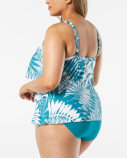 Model wearing a plus sized triple tiered tankini top in a turquoise and white abstract palm frond print