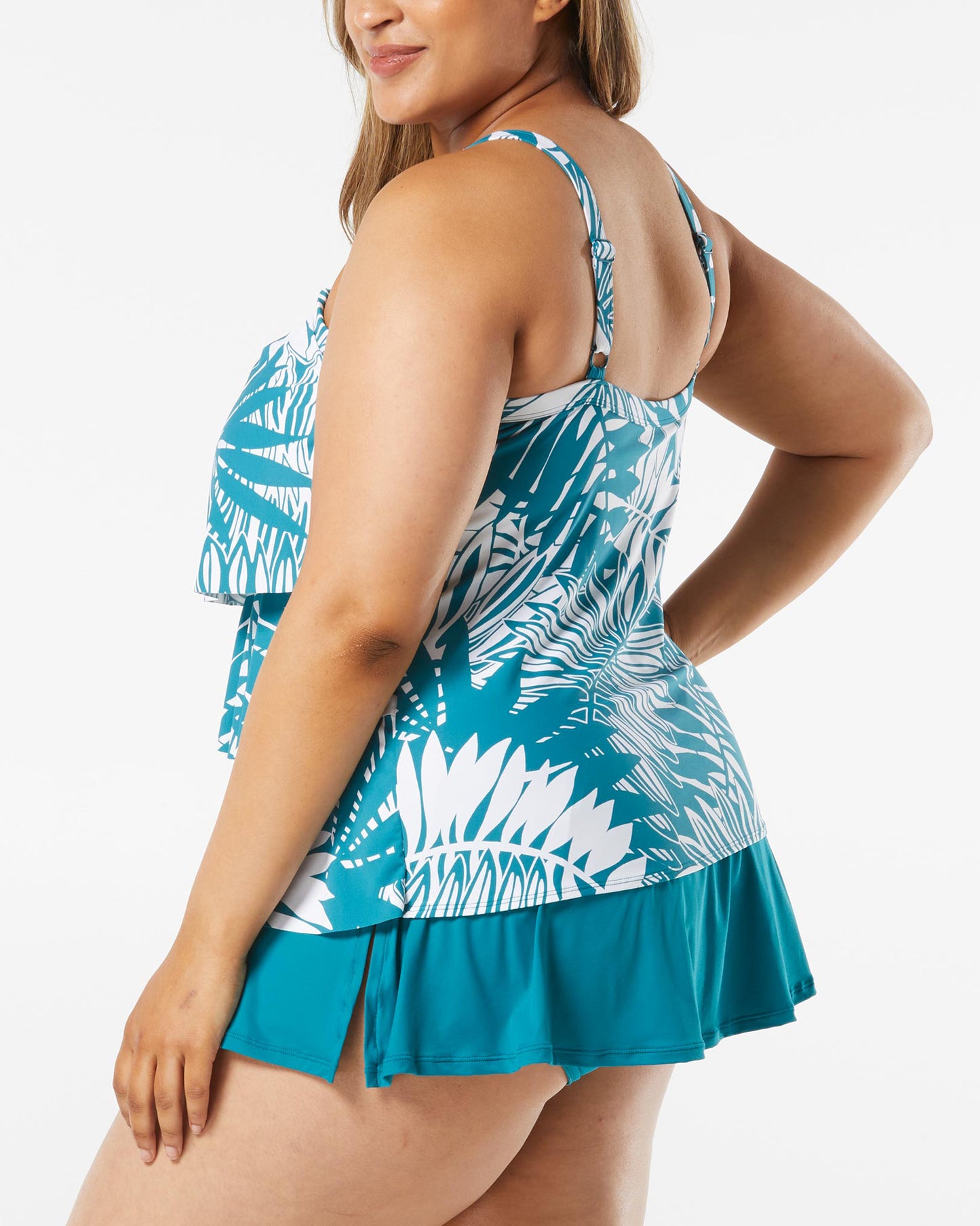 Model wearing a plus sized triple tiered tankini top in a turquoise and white palm frond print