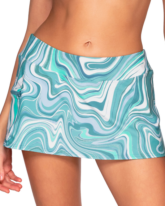 Model wearing a swim skirt with a pocket and hidden short in a pale turquoise and white swirl print.
